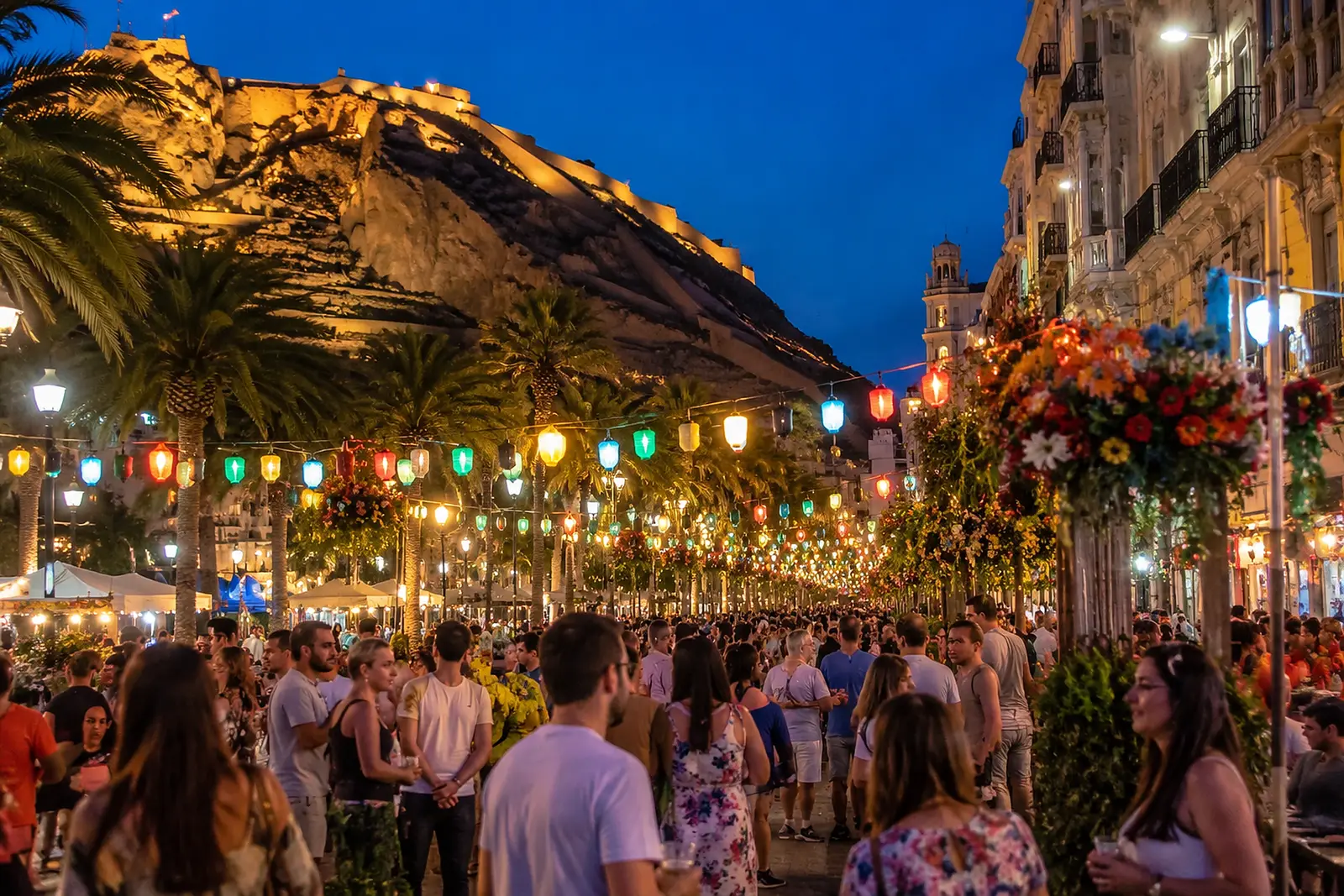 Kvällsfestival i Alicante med ljus, palmer och människor på gatan